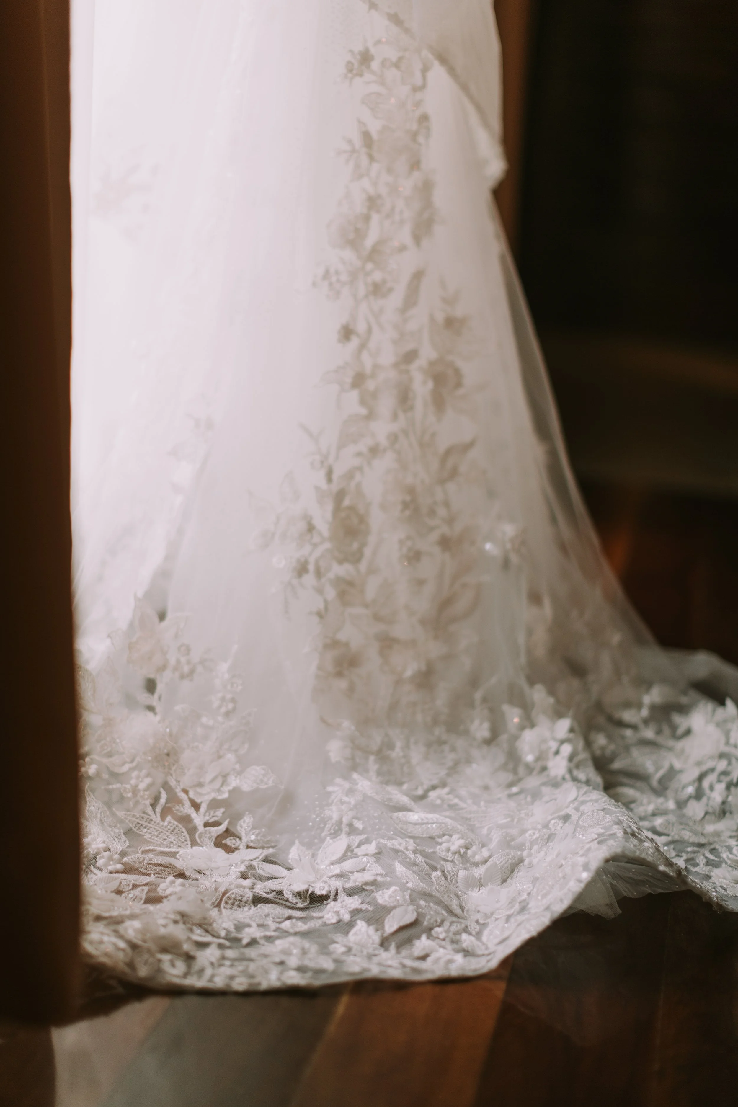 Embroidered lace train of Emily's gown pooling over dark wood at Hideaway Rio Celeste, Costa Rica