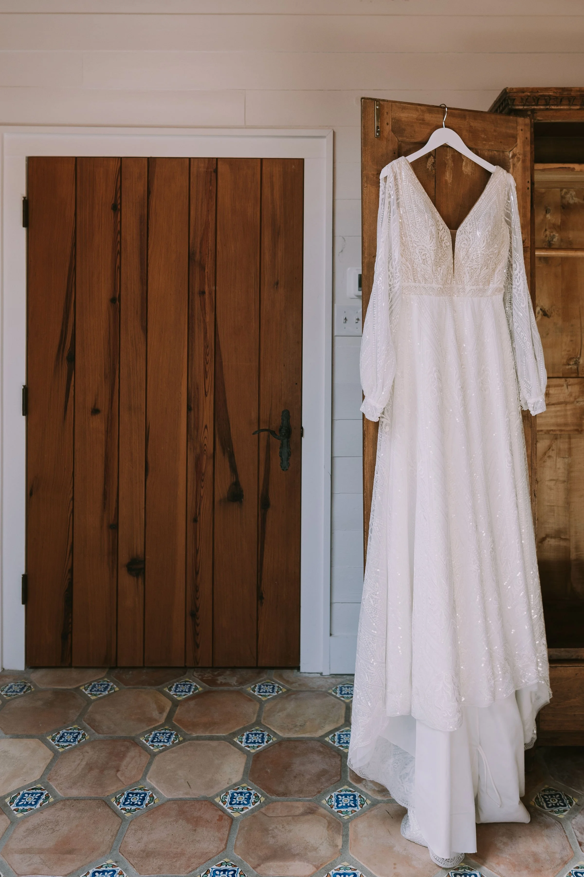 Beaded long-sleeve gown hangs in the bridal suite before a Wimberley, Texas wedding