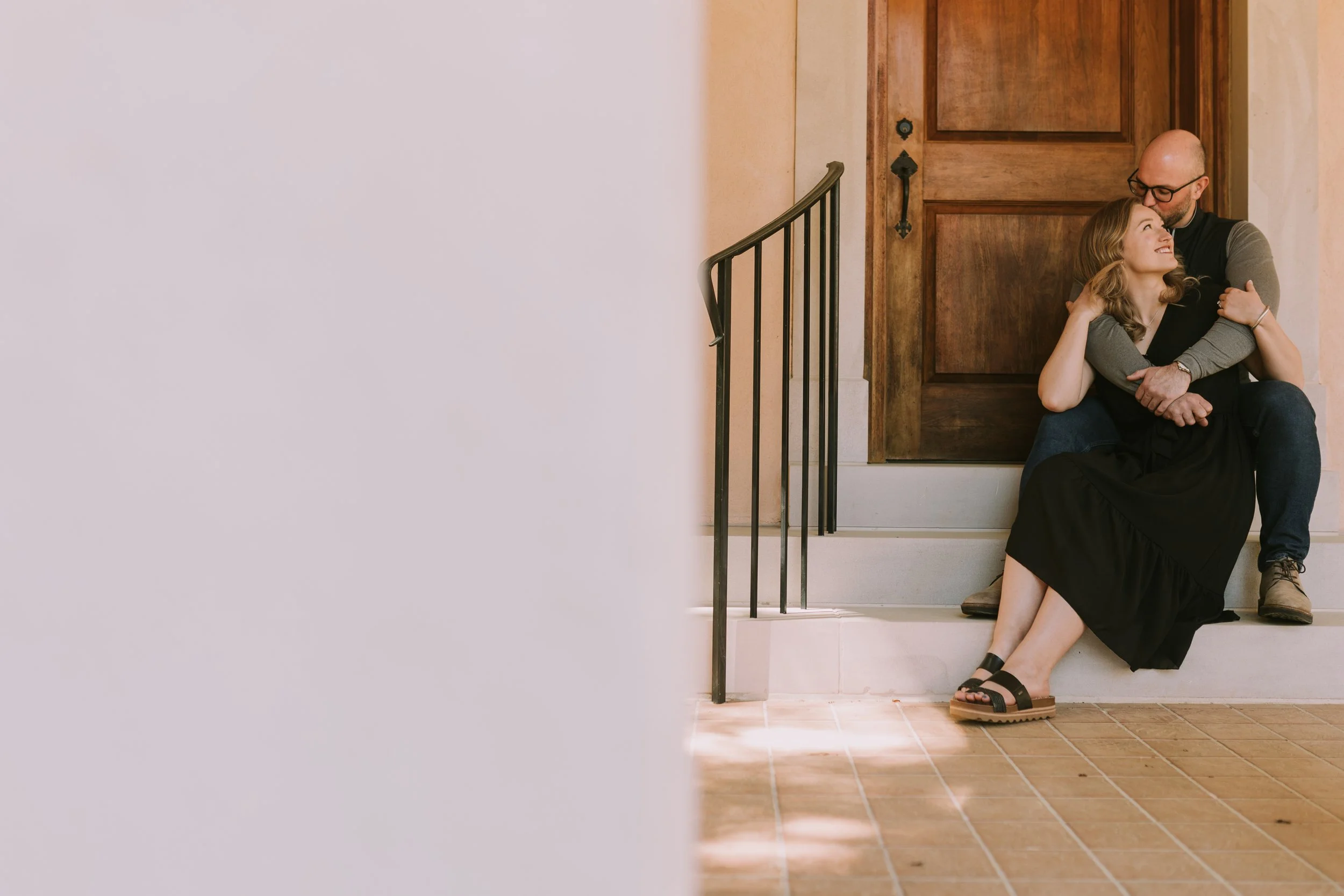 Maddie and Will sit close on stucco steps beside a carved wood door in Charlotte, North Carolina