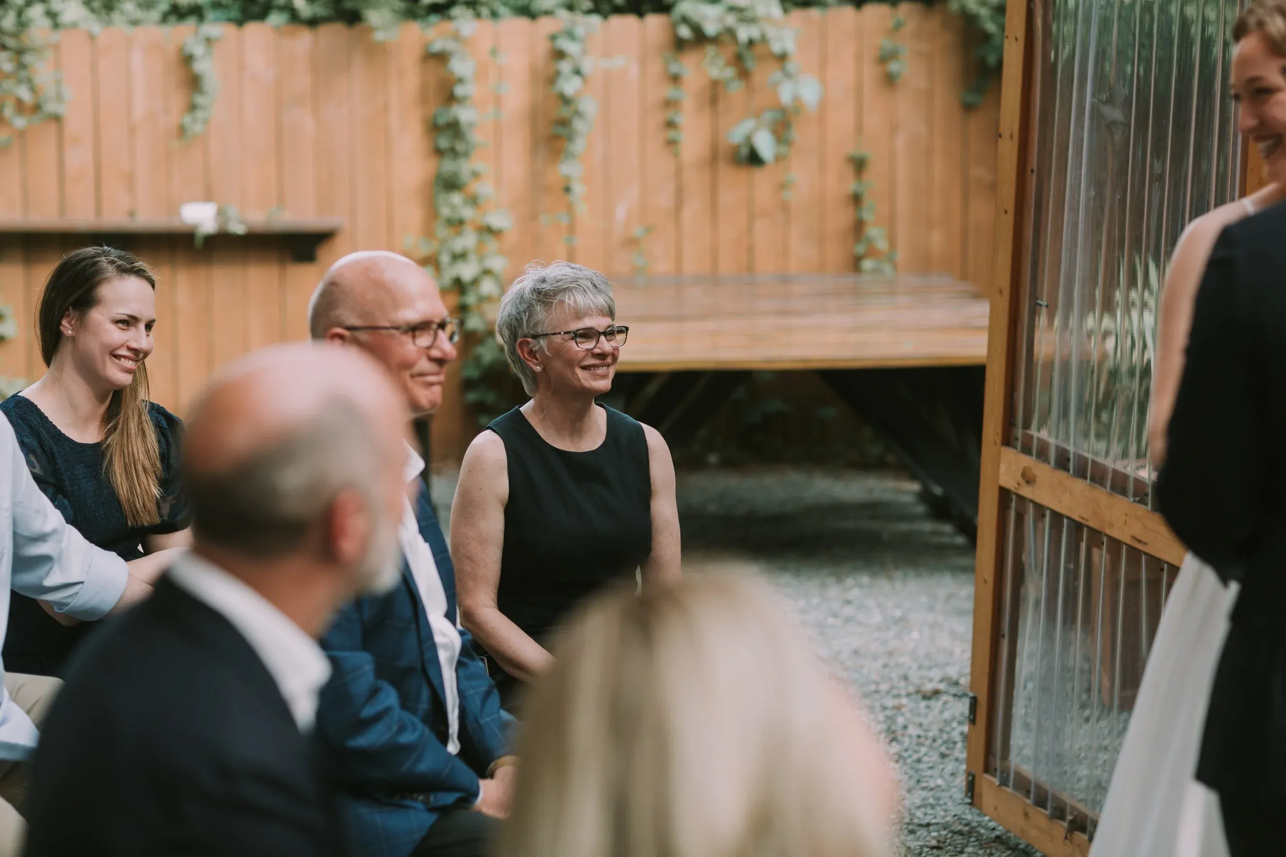 Parents smiling from the front row of an ivy walled courtyard ceremony in Charlotte, North Carolina